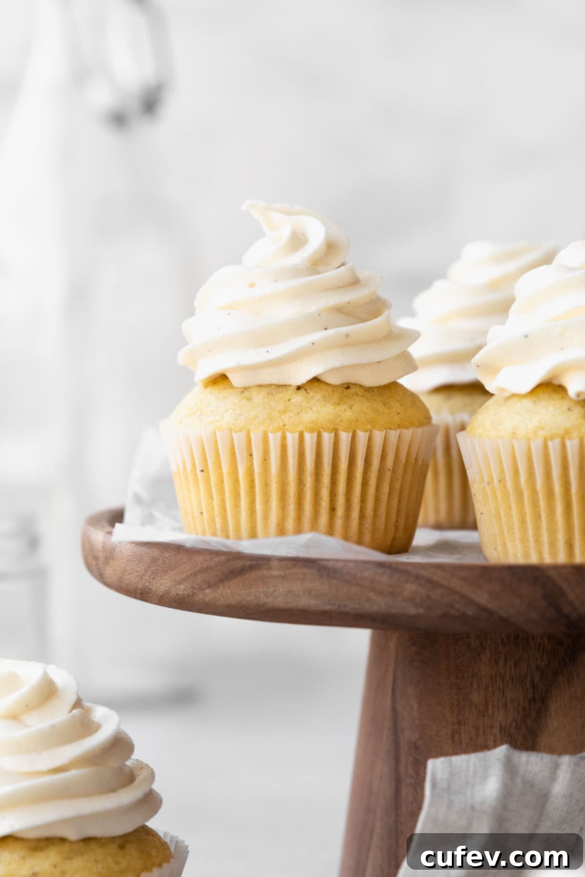 Dairy-free vanilla cupcakes on a wooden cake stand.