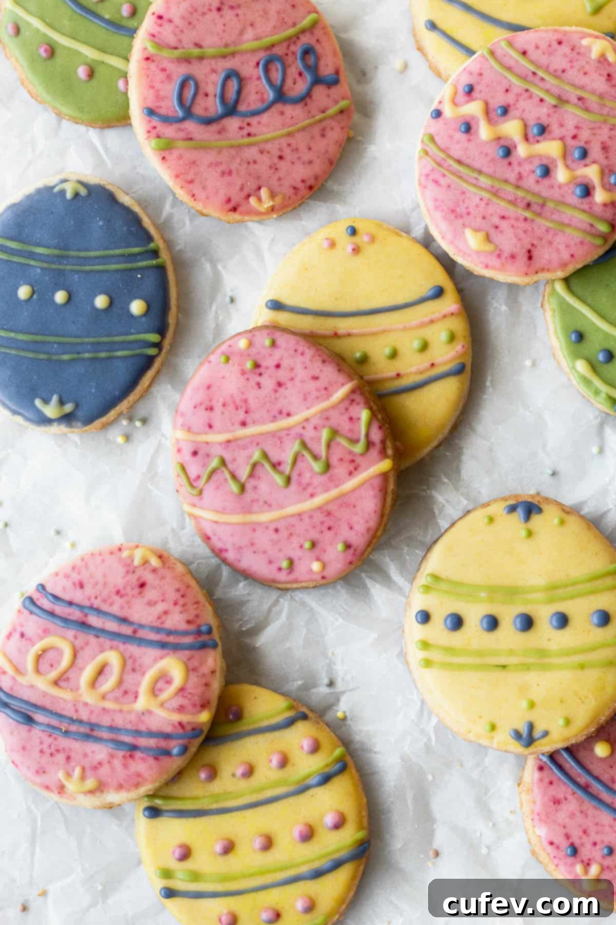 Easter egg sugar cookies decorated with different colored icing on parchment paper.