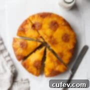 Tropical Gluten-Free Pineapple Upside Down Dream 5 A sliced gluten-free pineapple cake on a white surface with a linen and a knife.