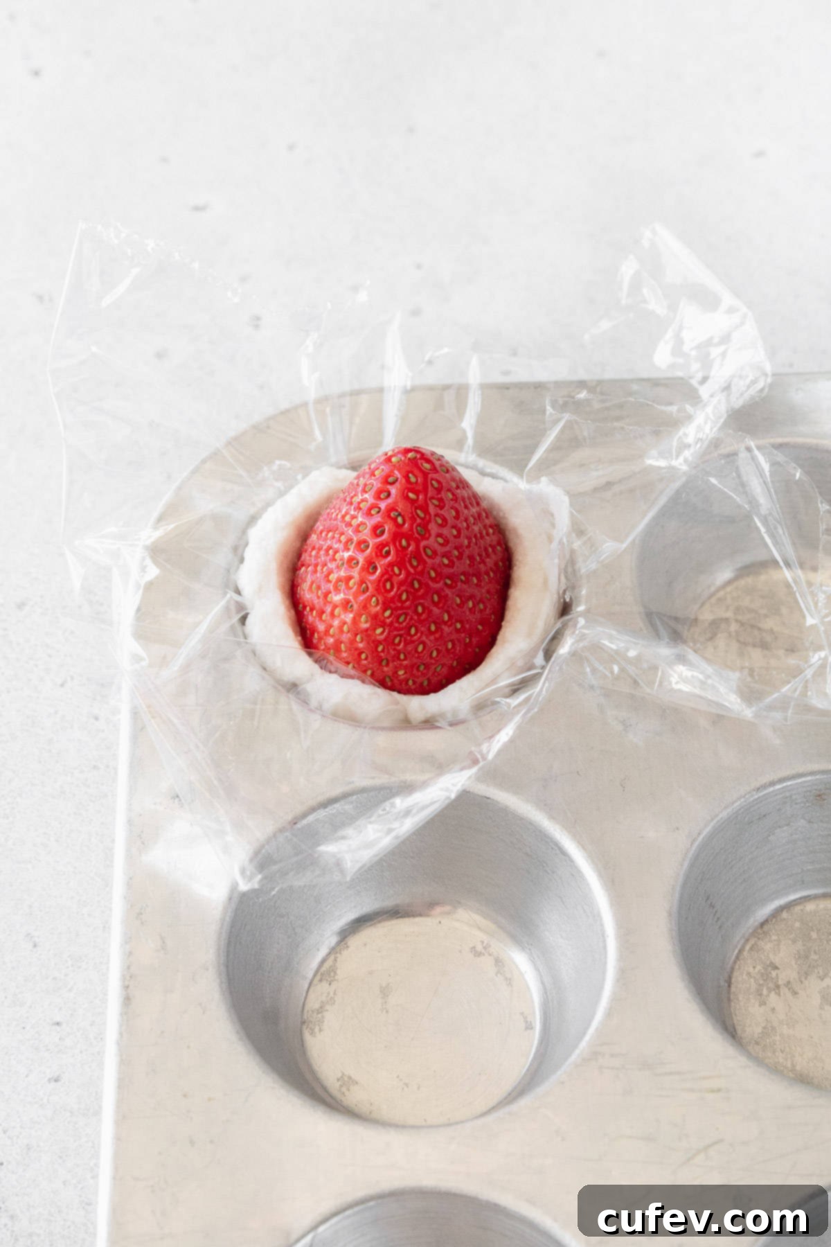 Fresh Japanese Strawberry Mochi 17 A strawberry put into a portion of whipped cream with the tip of the strawberry pointing up.