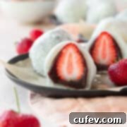 Fresh Japanese Strawberry Mochi 21 A sliced strawberry mochi on a black plate.