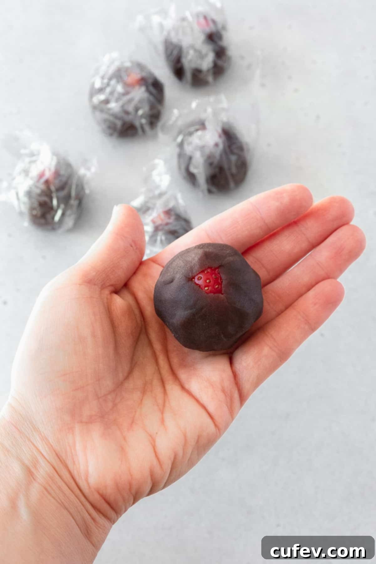 Fresh Japanese Strawberry Mochi 6 A strawberry wrapped in anko on the palm of a hand.