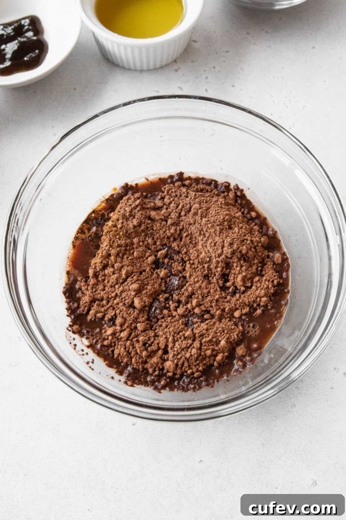 Dutch-processed cocoa powder and instant coffee dissolving and blooming in hot water within a clear glass bowl, showcasing the deepening of chocolate color.