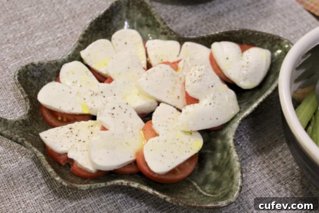 Fresh Caprese salad with heart-shaped mozzarella slices on tomato.