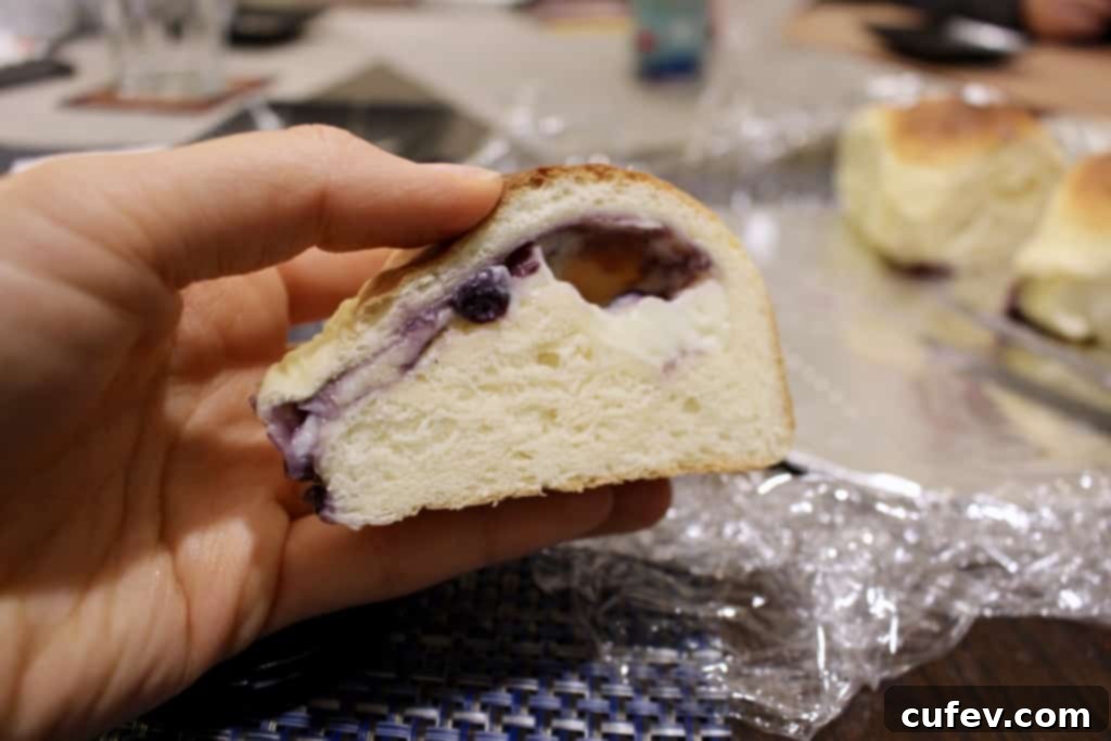 A sliced blueberry cream cheese bun showing the creamy filling, highlighting a small leak from improper sealing.