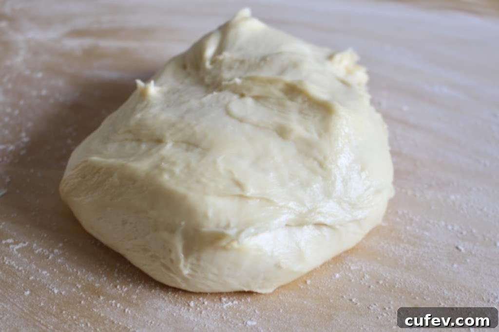 Close-up of fluffy sweet roll dough being prepared on a floured surface for blueberry cream cheese buns.