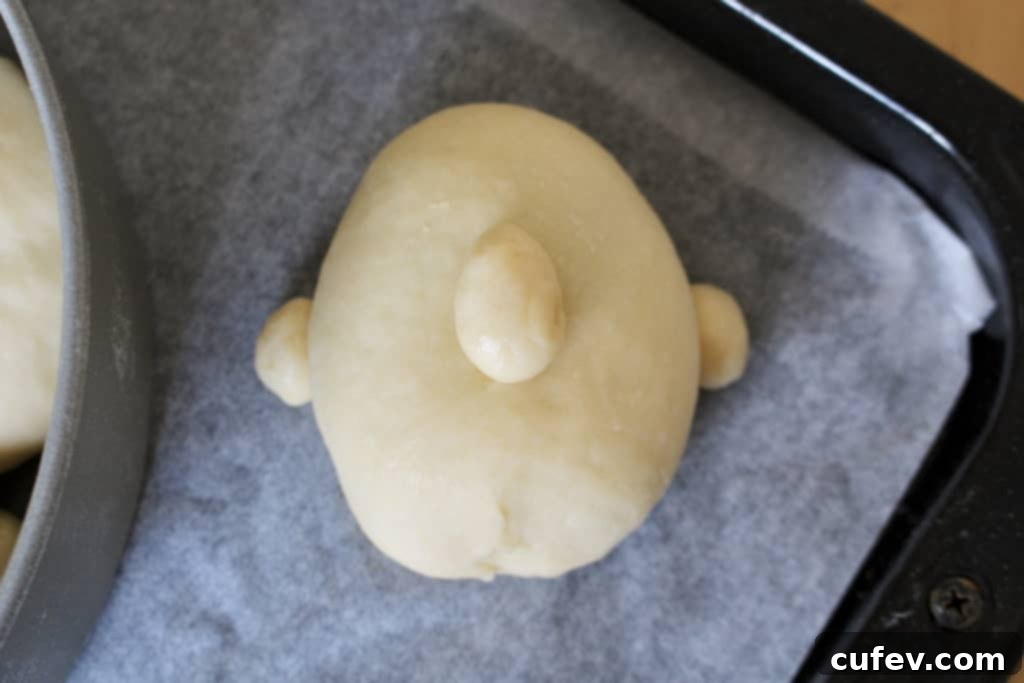 Shaping the blueberry cream cheese bun into a face, adding small pieces of dough for ears and nose before rising.