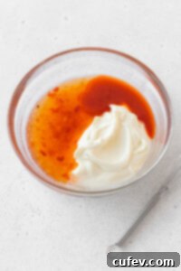 Mayo, sweet chili sauce, sriracha, and rice vinegar in a glass bowl.