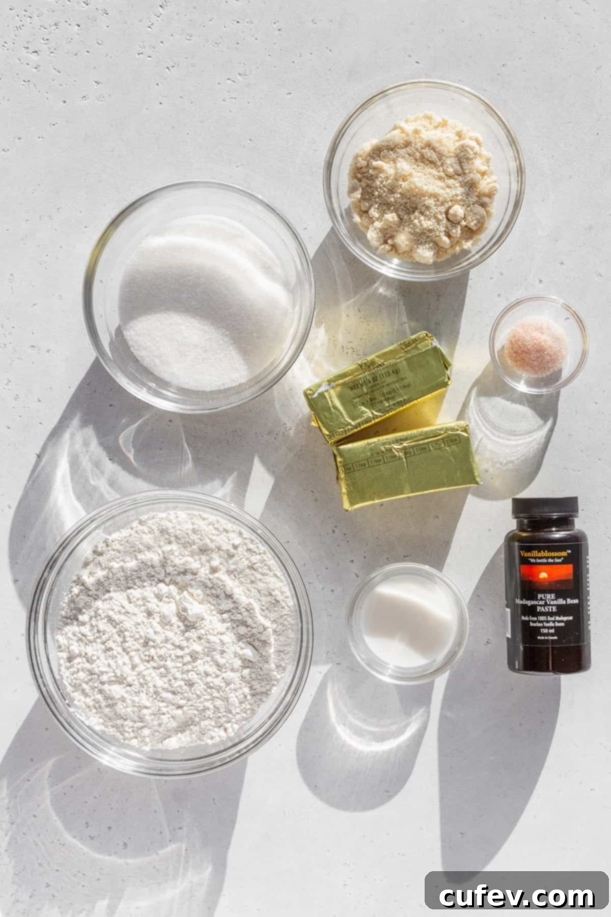 Ingredients for gluten free sugar cookies measured out into bowls on a white surface.