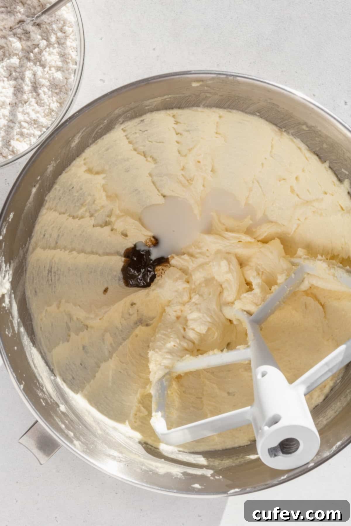 Creamed butter and sugar in the bowl of a stand mixer, with a splash of vanilla extract and milk.