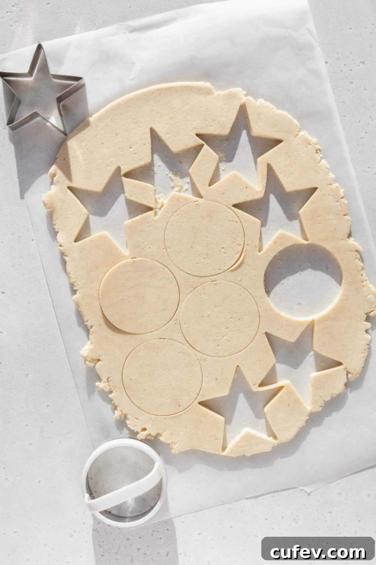 Shapes being cut out of rolled out sugar cookie dough.