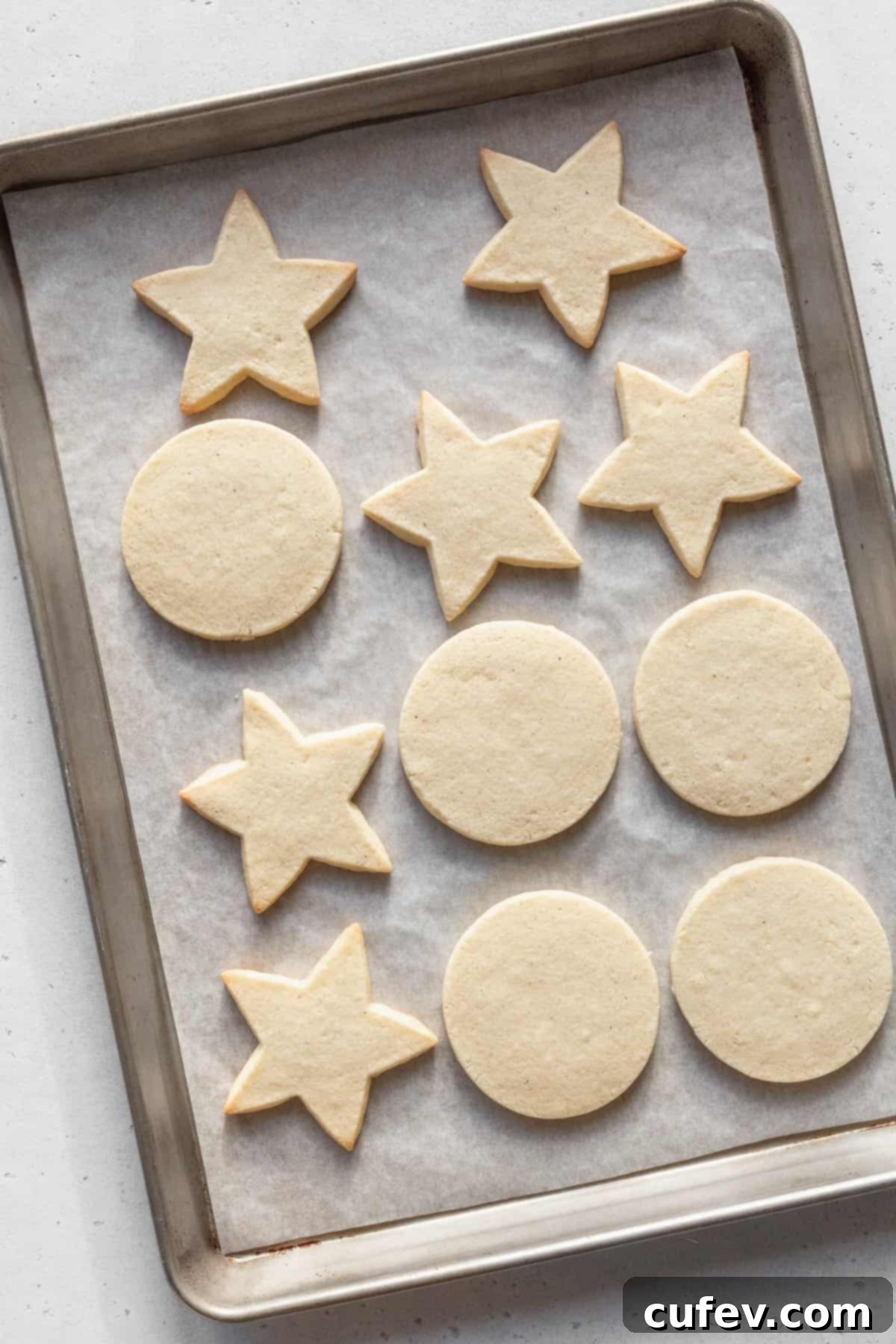 Baked gluten-free sugar cookies on a parchment paper lined baking sheet.
