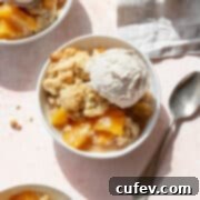 A bowl of peach cobbler with canned peaches and a scoop of vanilla ice cream.
