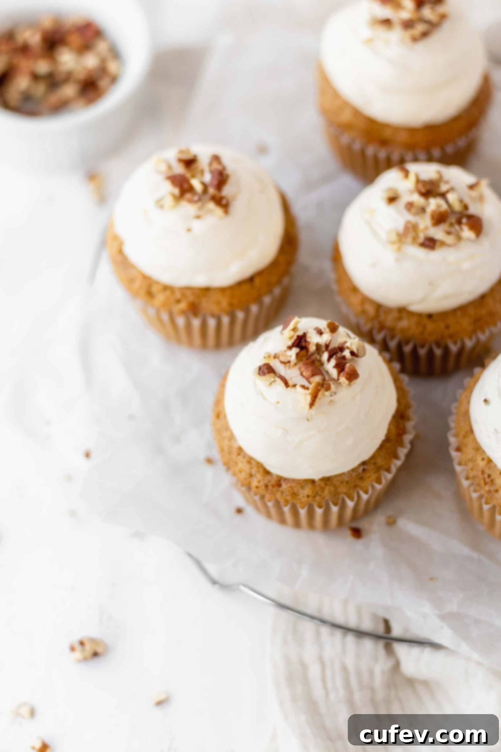 Cream cheese buttercream on carrot cupcakes with chopped pecans on top