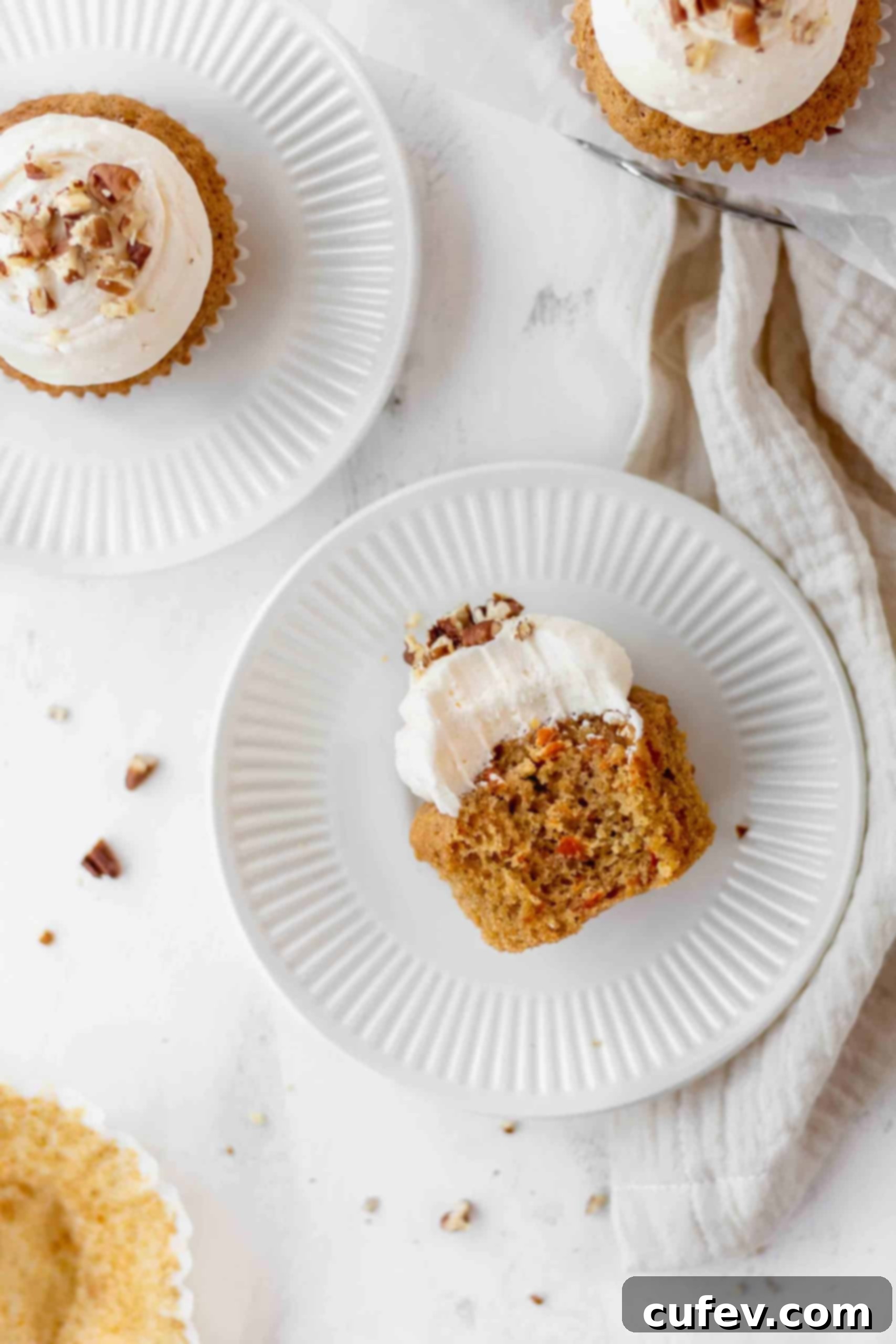 A bitten cupcake with lemon cream cheese frosting on a plate
