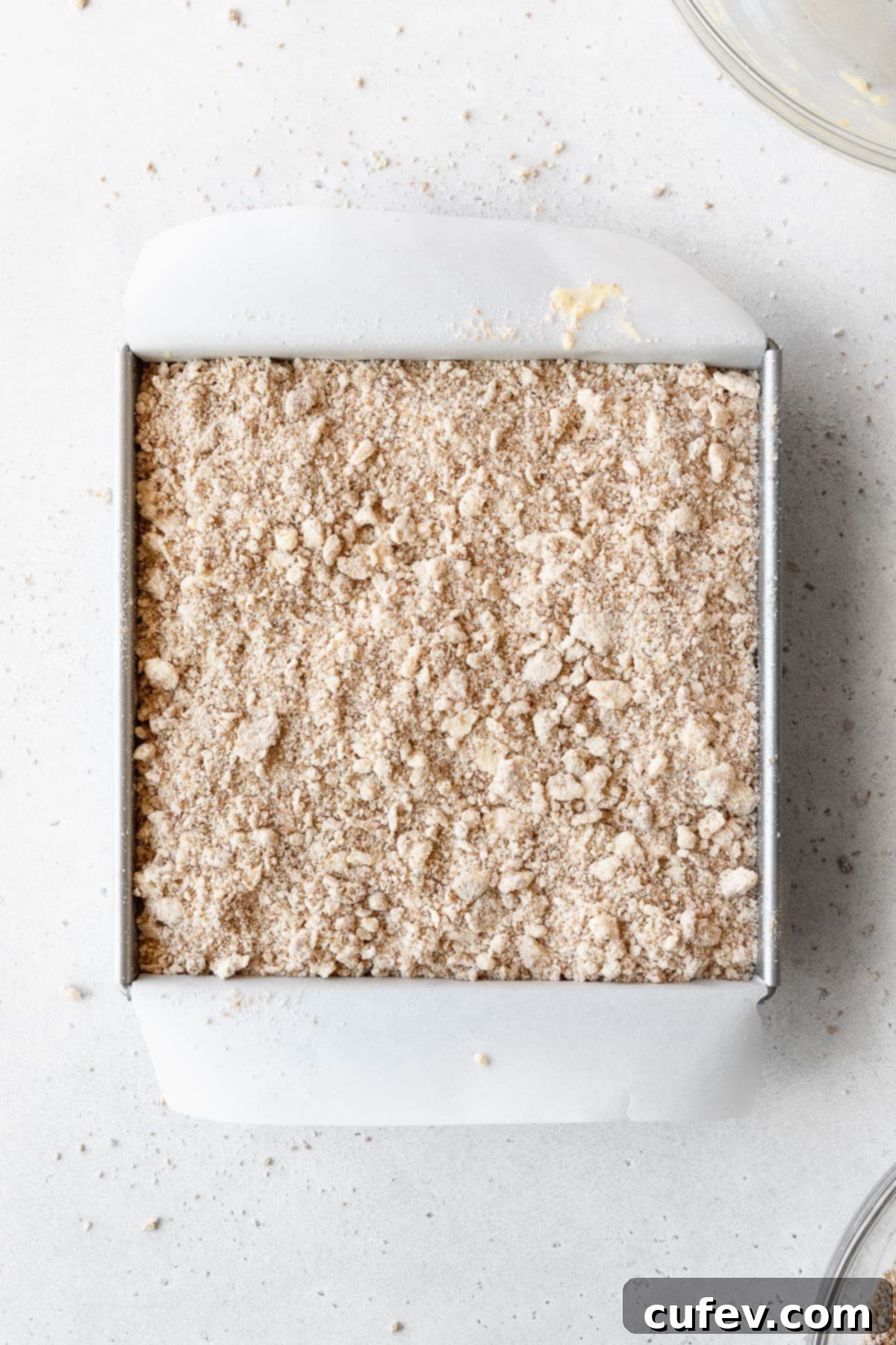 Cake batter topped with crumb topping in a square pan ready to be baked.