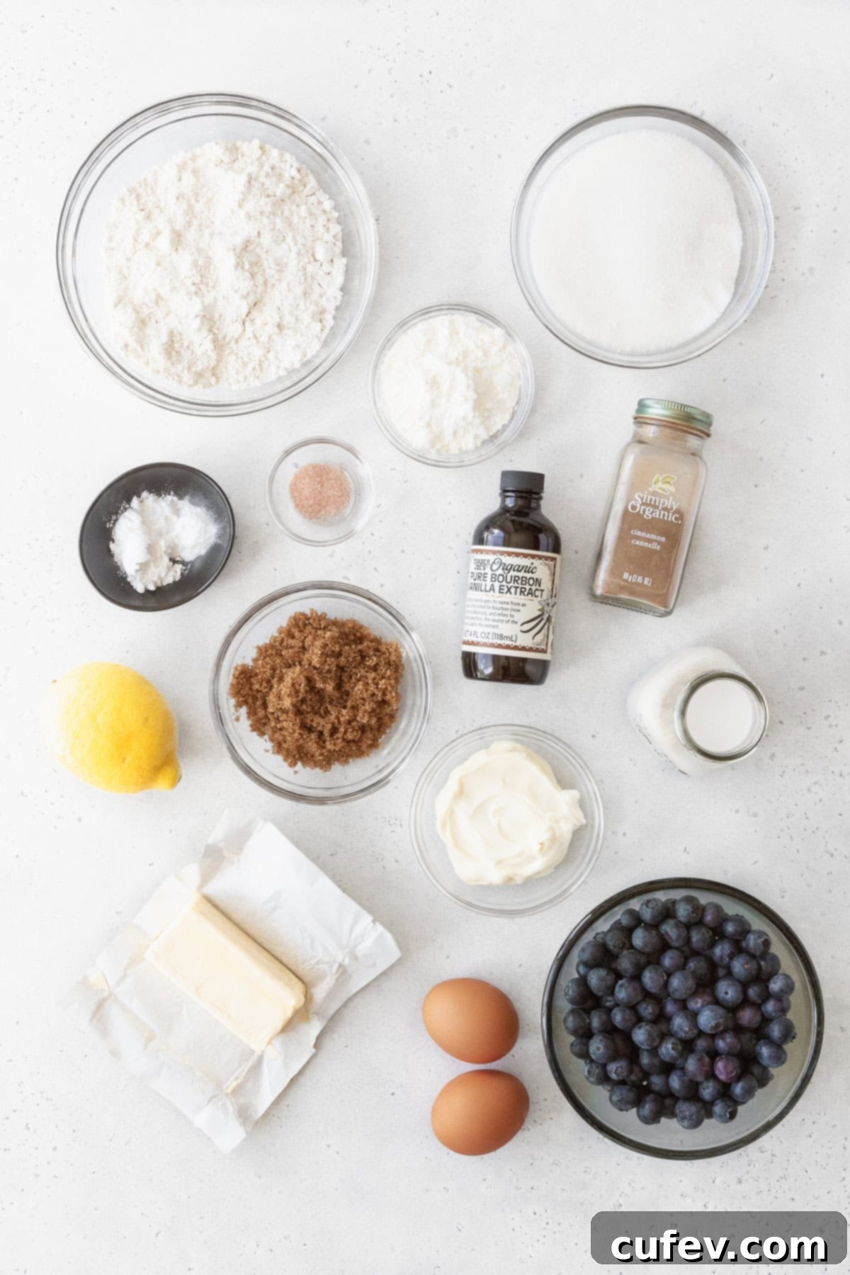 Ingredients for blueberry coffee cake measured out into bowls on a white surface.