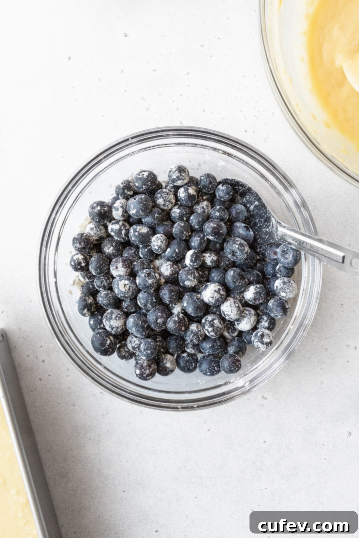 Fresh blueberries in a glass bowl tossed with flour.