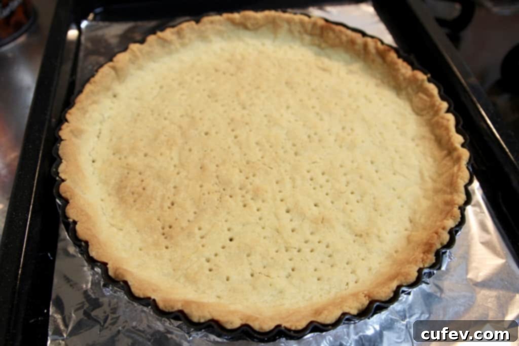 Golden brown, flaky tart crust baking in a tart pan, ready for filling with grapefruit curd.