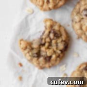 A bitten gluten-free oatmeal cookie with chocolate chips on a white surface surrounded by more cookies.
