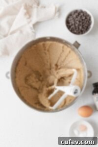 Creamed butter and sugar in a metallic bowl with a white beater inside.