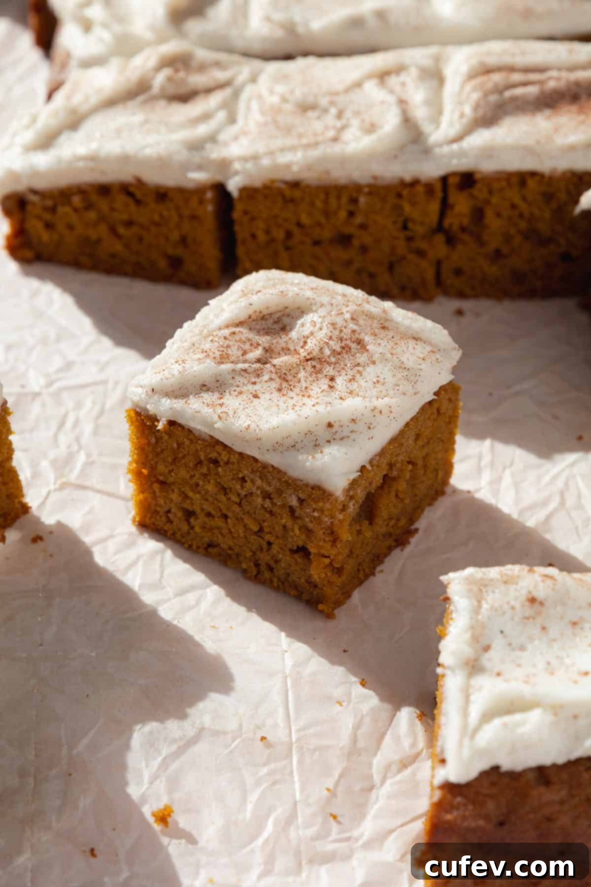 Autumn Spiced Pumpkin Squares 2 A perfectly sliced pumpkin bar topped with creamy white cream cheese frosting, ready to be enjoyed.