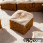 Autumn Spiced Pumpkin Squares 14 A delicious pumpkin bar with cream cheese frosting, lightly dusted with cinnamon, showcasing its autumnal appeal.