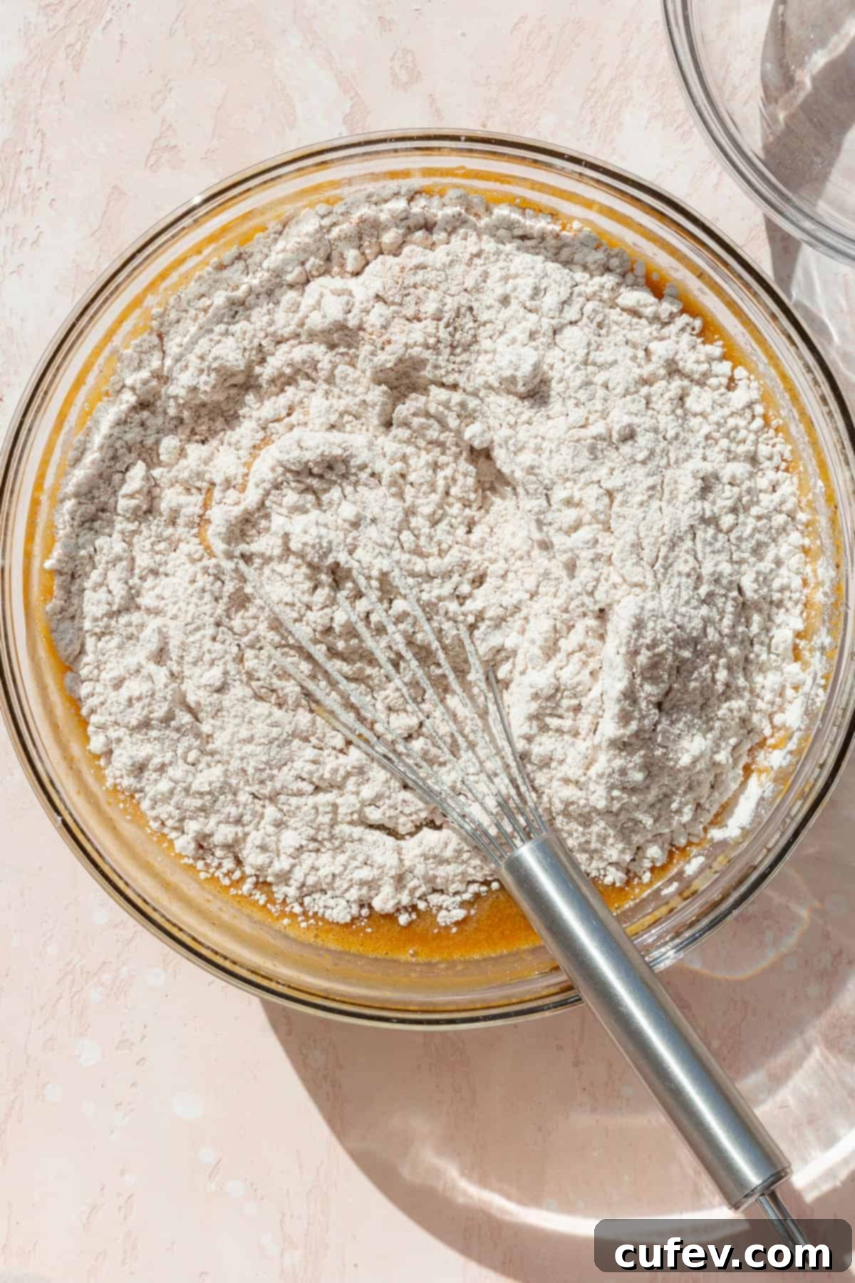 Autumn Spiced Pumpkin Squares 7 Dry ingredients being gently whisked into the wet ingredients in a glass bowl, showcasing the mixing process.