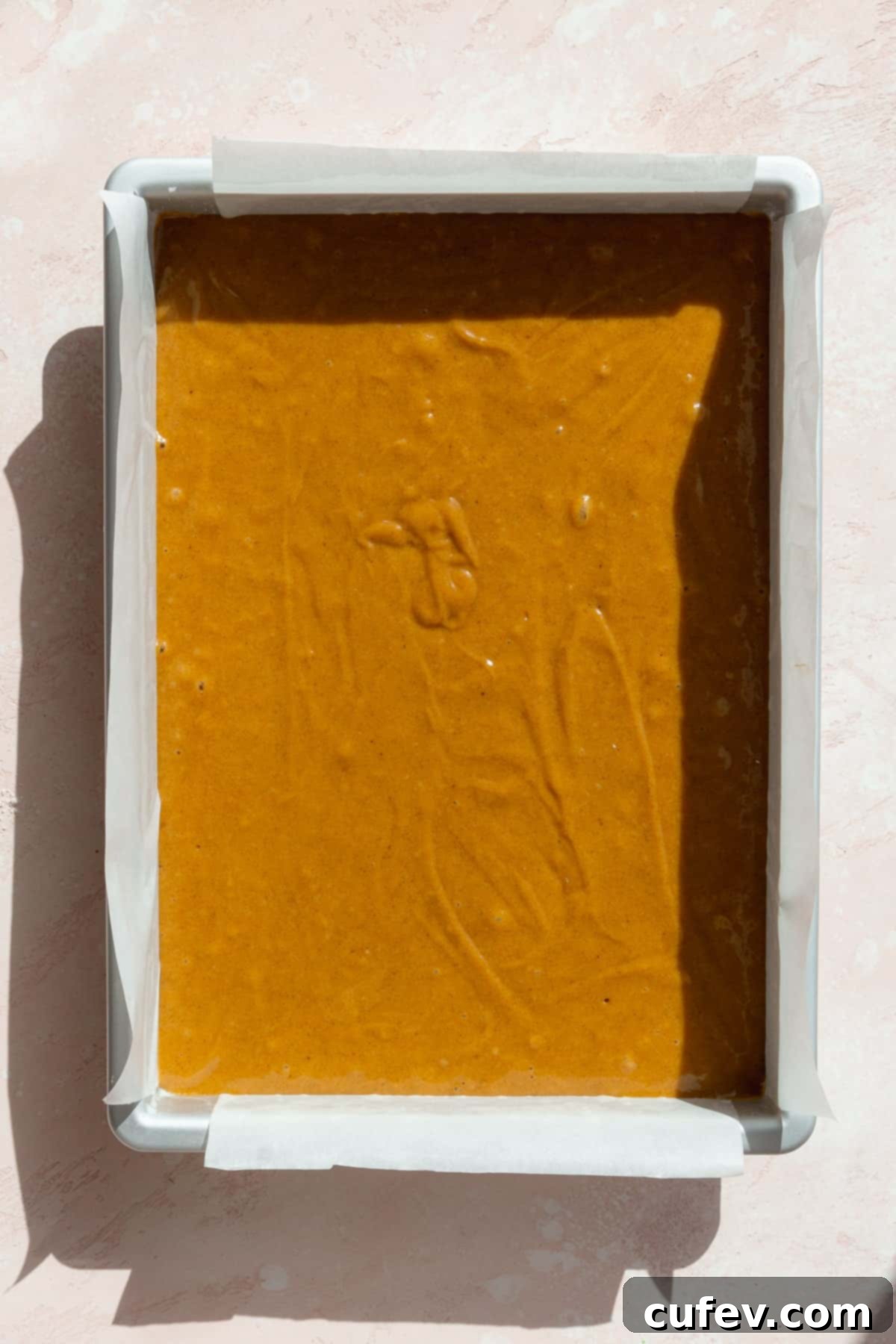 Autumn Spiced Pumpkin Squares 9 Smooth pumpkin bar batter carefully poured into a 9x13 inch baking pan, lined with parchment paper, ready for baking.