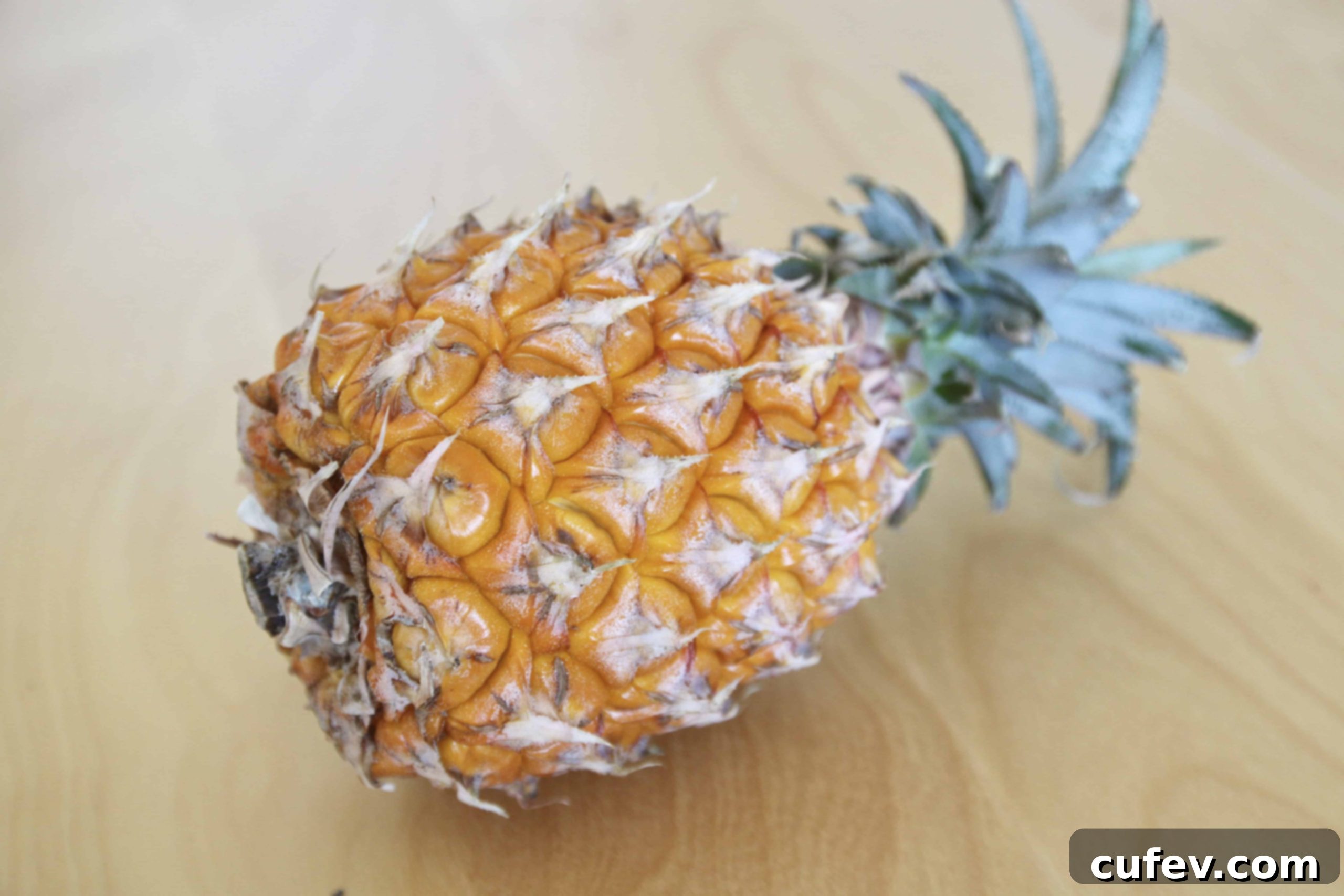 A ripe, whole pineapple lying on its side, ready to be prepared for the filling.