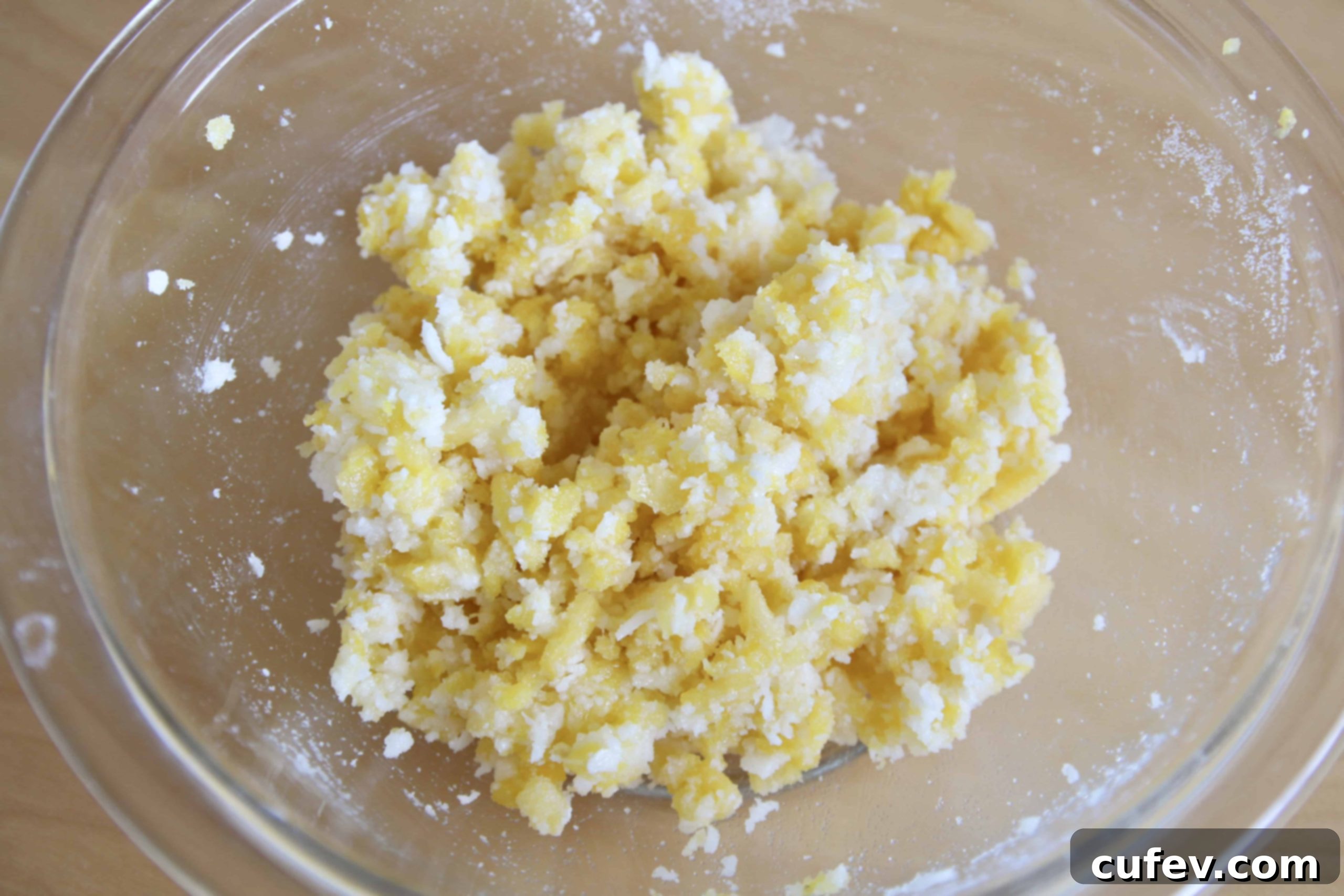 A glass bowl filled with finely chopped pineapple and desiccated coconut, ready for the sweet roll filling.