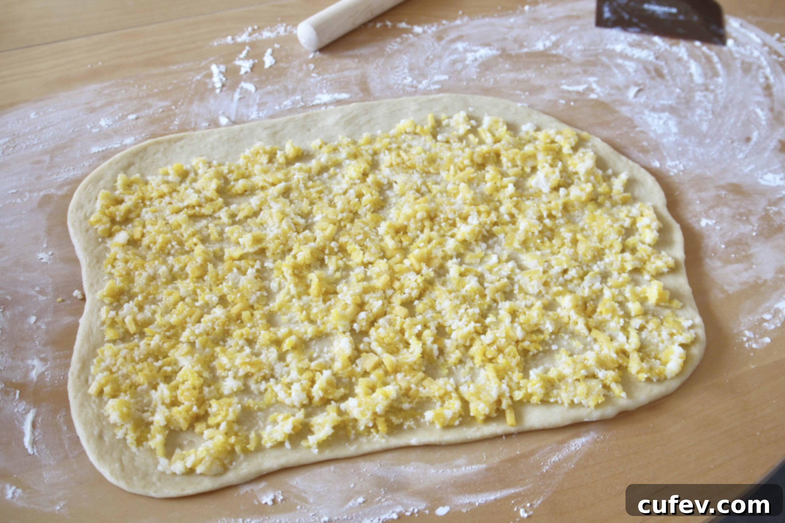 Sweet roll dough spread with pineapple and coconut filling, ready to be rolled up and sliced into individual rolls.