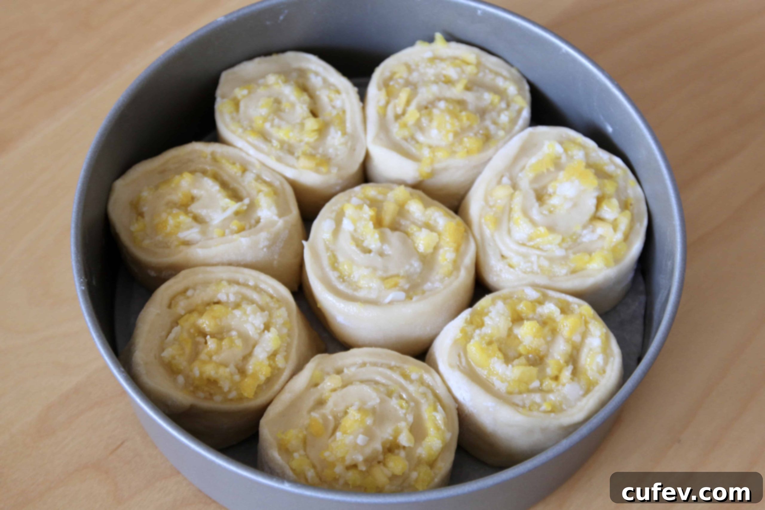 Piña colada sweet roll dough arranged in an 8-inch cake pan, rising before baking.