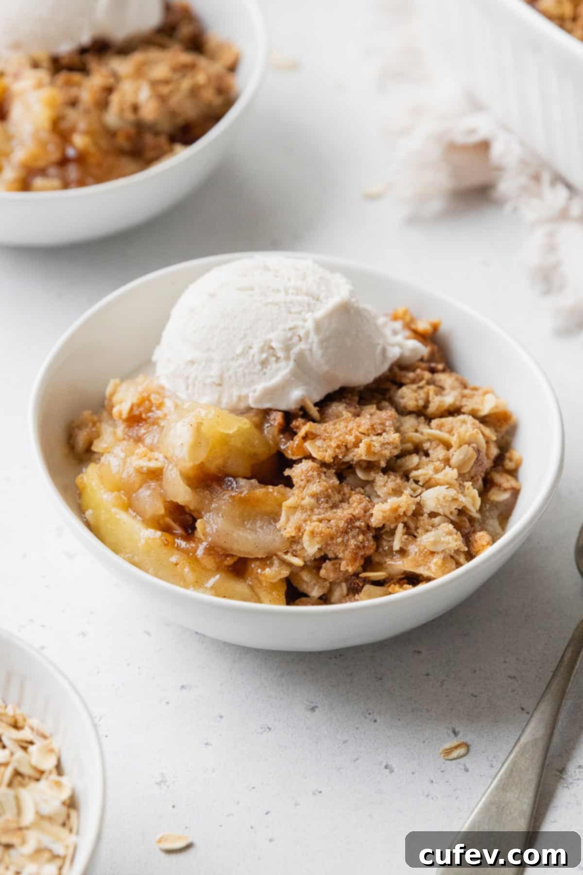 Comforting Gluten-Free Apple Crumble 10 Apple crisp in a white bowl with a scoop on vanilla ice cream on top.