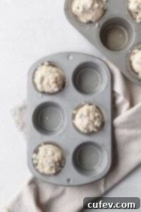 Muffin tins with blueberry muffin batter in every other muffin cup.