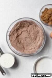 Dry ingredients for gluten-free chocolate cake, including flour, cocoa, and leavening agents, perfectly sifted in a clear glass bowl.
