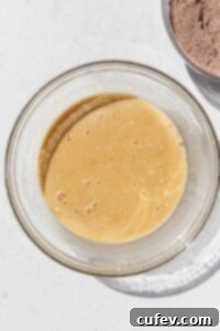 Wet ingredients for gluten-free chocolate cake, including eggs, buttermilk, sugars, and oil, expertly mixed in a large bowl.