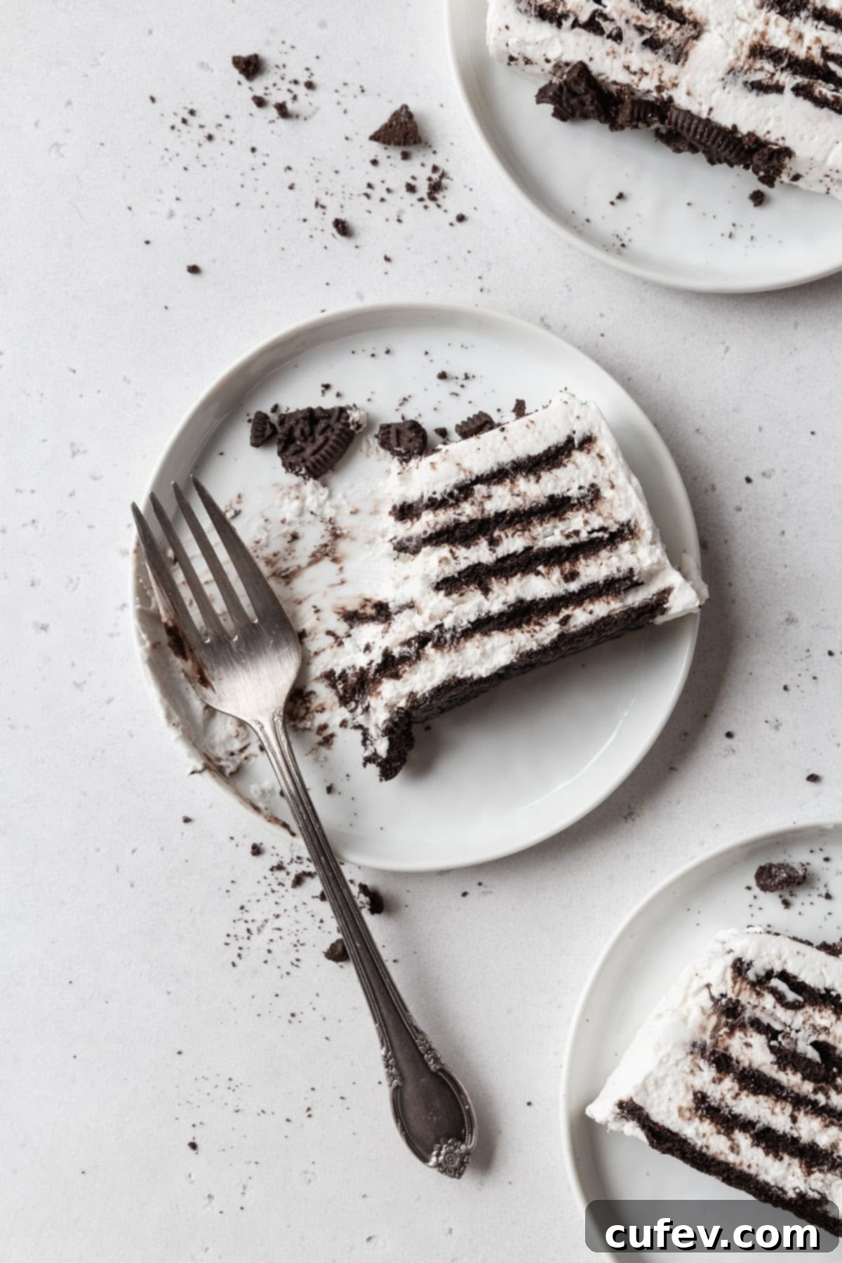 Velvet Chill Cake 9 A partially eaten slice of creamy icebox cake, showing the distinct cookie and cream layers, resting on a white plate with a fork beside it.