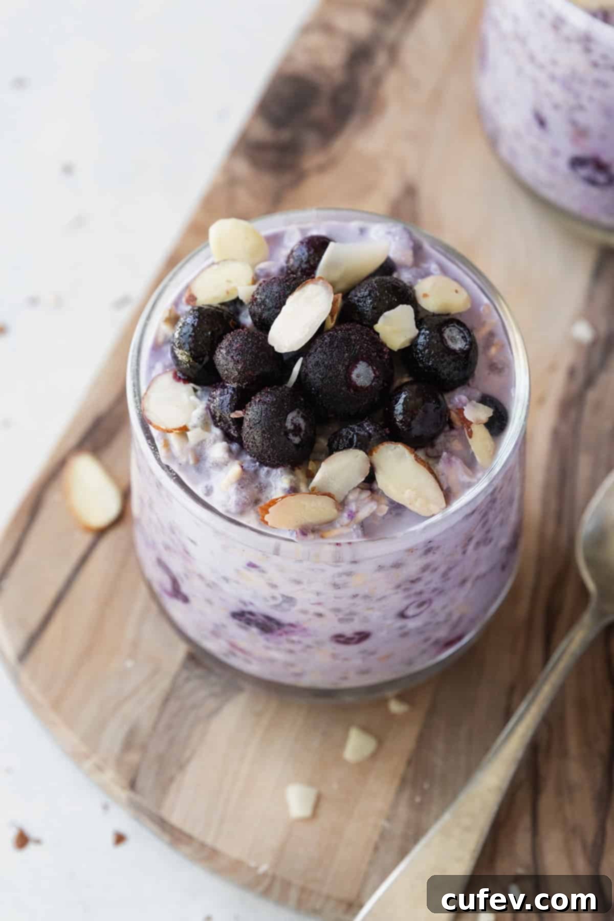 Wholesome Blueberry Overnight Oats 6 Frozen blueberries and sliced almonds on a glass of overnight oats, ready for serving.