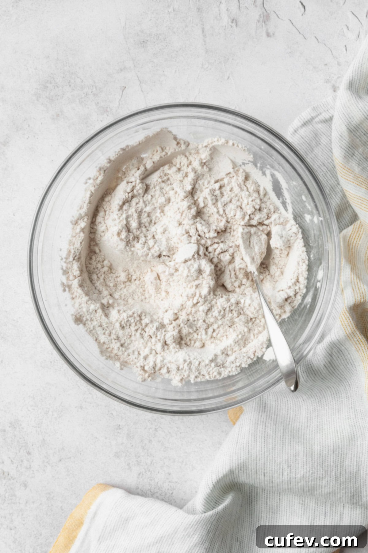 Dry ingredients in a glass bowl with a spoon.