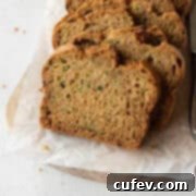 Slices of gluten-free zucchini bread on a wooden board lined with parchment paper.
