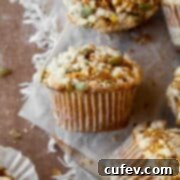 A gluten free pumpkin muffin with streusel topping and pumpkin seeds on a piece of parchment paper, highlighting its delicious texture.