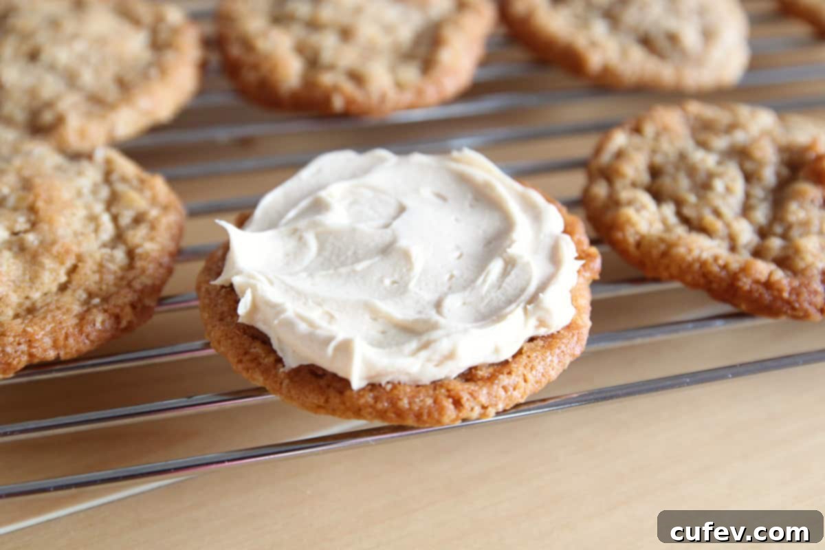 An oatmeal cookie on a wire rack with some buttercream frosting spread on top.