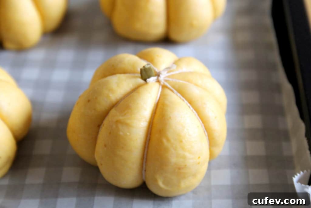 Shaping the pumpkin buns with oiled twine to create realistic pumpkin segments before baking.