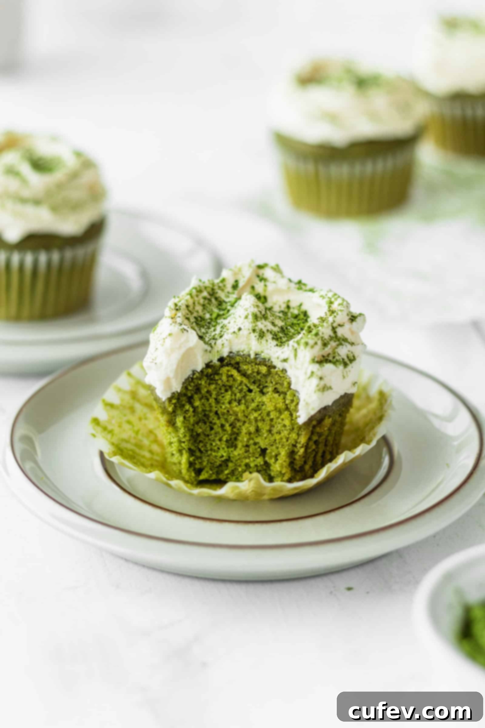 Fluffy green tea cupcake with a bite taken out, showing its tender crumb