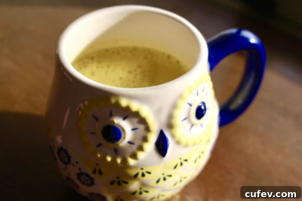 A comforting mug of golden milk, held by hands, with spices in the background