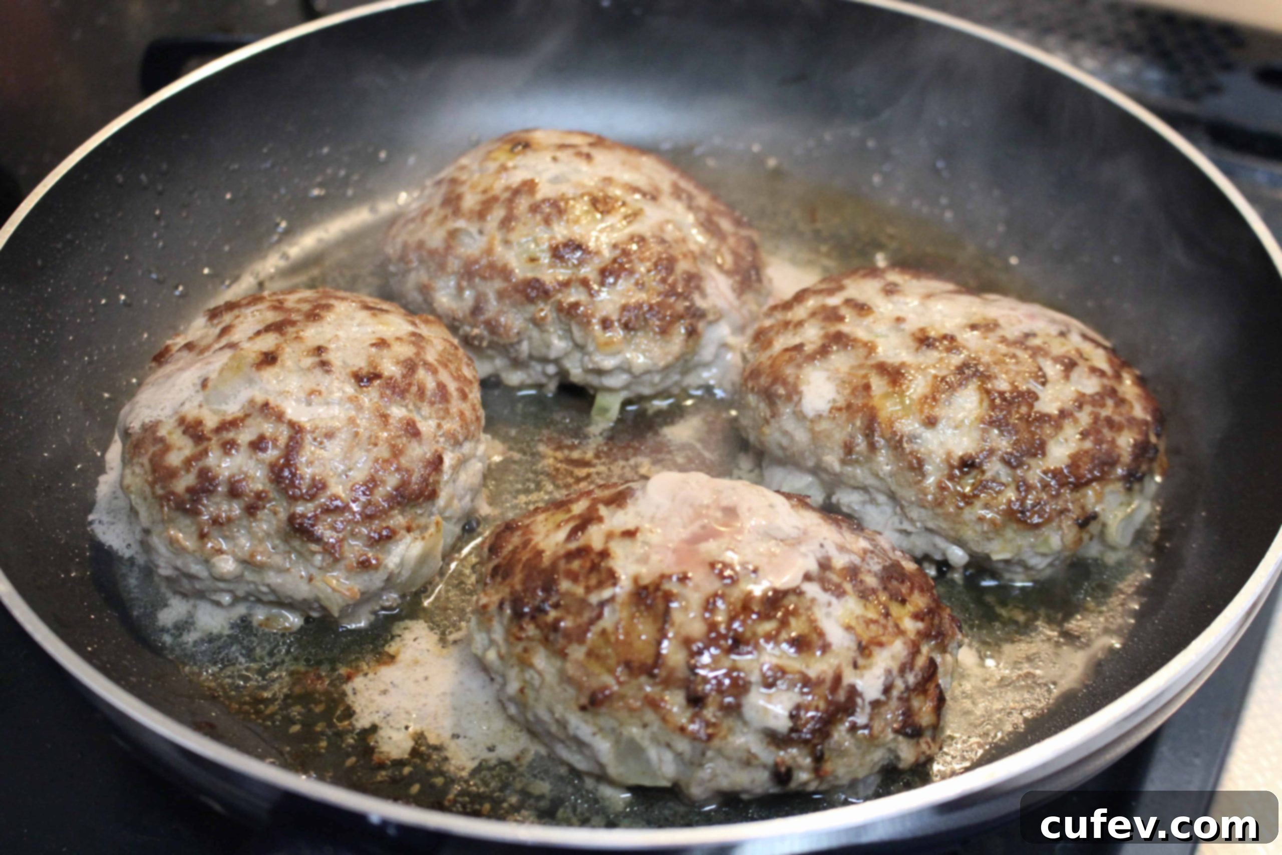 Salisbury steak patties cooking in a non-stick pan, covered to lock in moisture