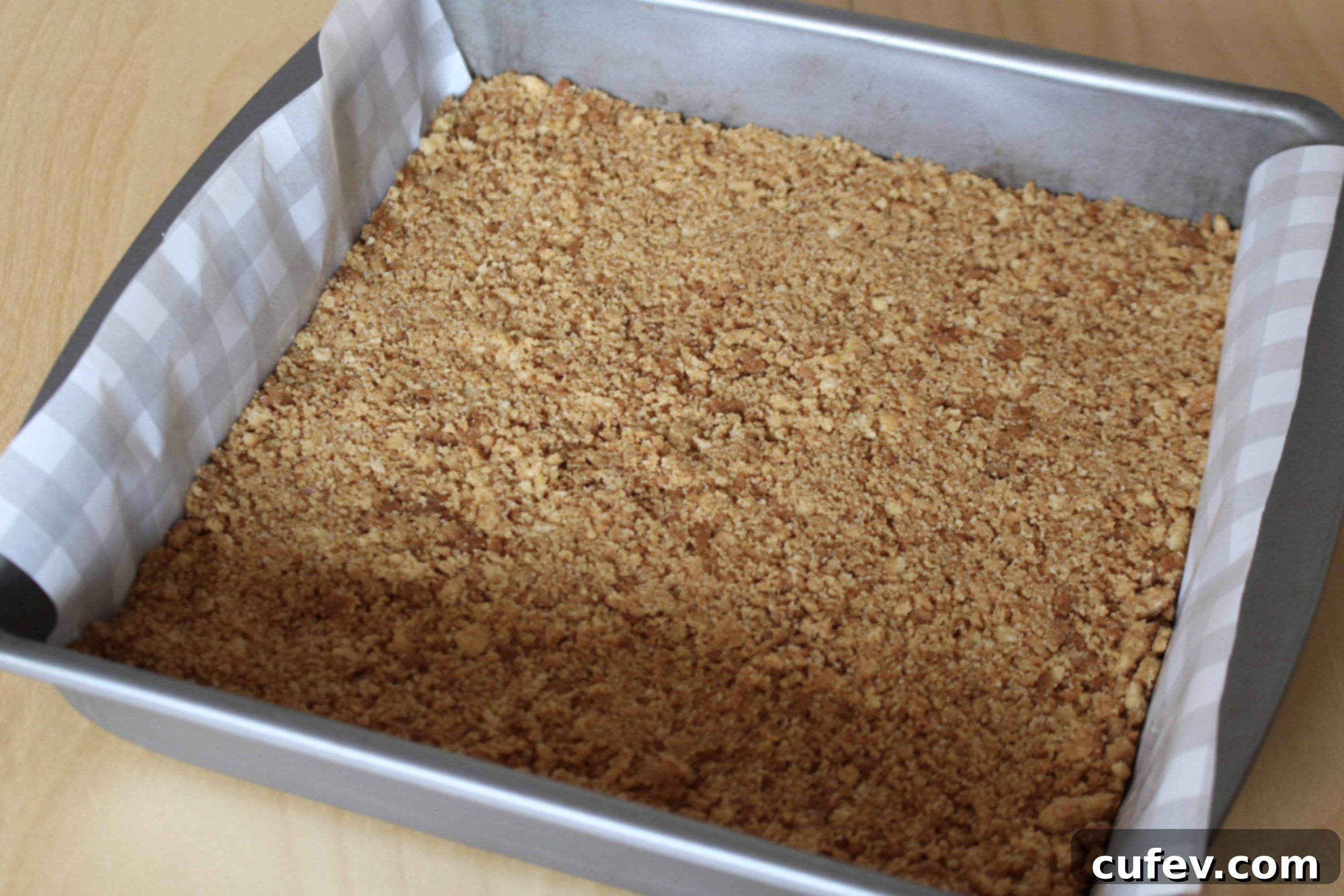 Preparing the buttery biscuit crust for cheesecake bars