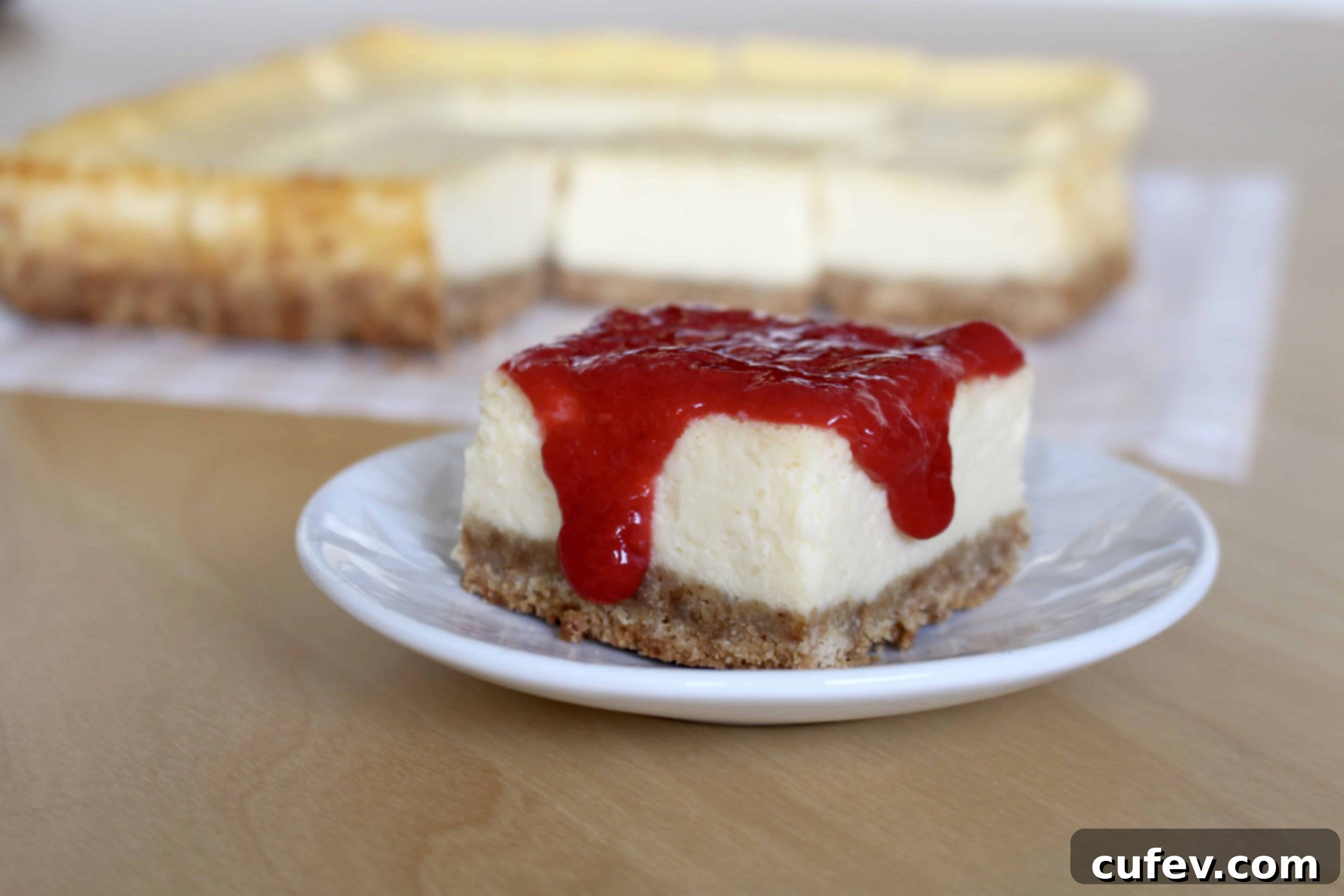 Cheesecake bars topped with fresh raspberry sauce