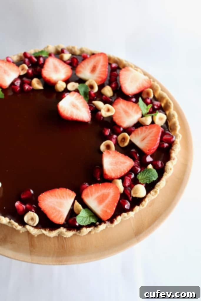 Velvet Bailey's Chocolate Delight 2 A stunning Bailey's chocolate tart with a salted oat crust, topped with fresh strawberries, pomegranate seeds, and roasted hazelnuts, perfect for a special occasion.